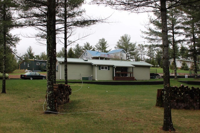rear view of house with a yard, cooling unit, and metal roof