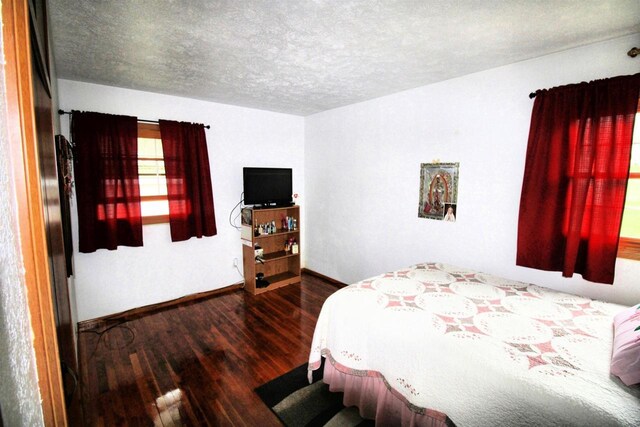 bedroom featuring baseboards, a textured ceiling, and wood finished floors