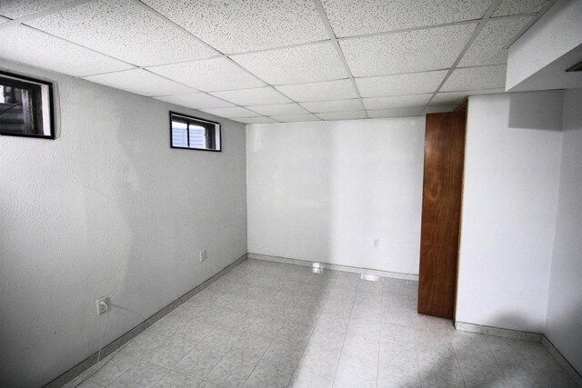 below grade area with baseboards and a drop ceiling