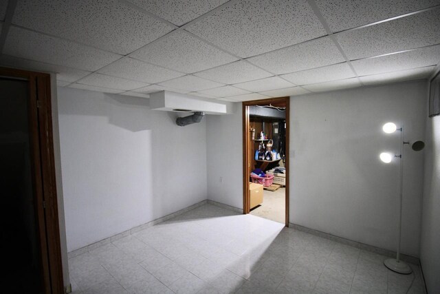 finished below grade area with baseboards, tile patterned floors, and a paneled ceiling