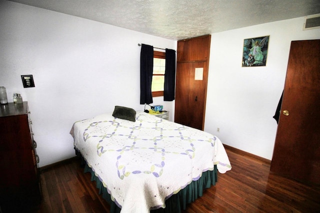 bedroom with visible vents, a textured ceiling, dark wood-style flooring, and baseboards