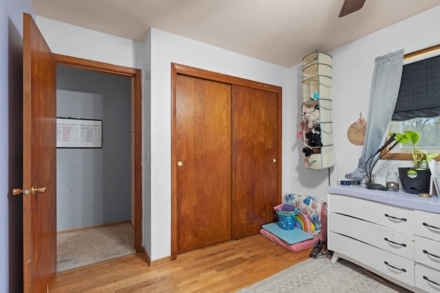 bedroom featuring ceiling fan, light wood finished floors, and a closet