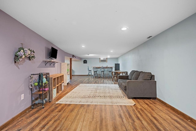 living room with recessed lighting, baseboards, wood finished floors, and bar area