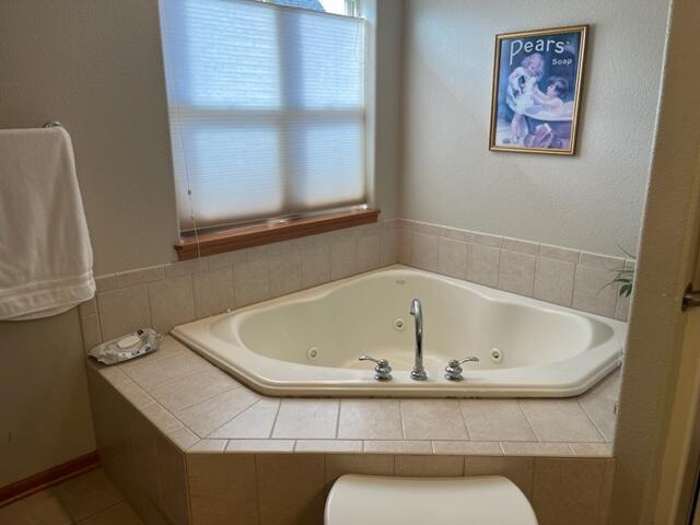 full bathroom with toilet and a tub with jets