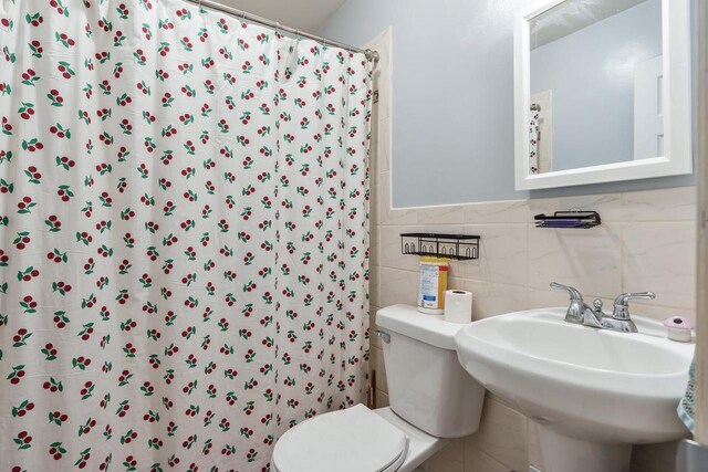 bathroom featuring toilet, a sink, and curtained shower