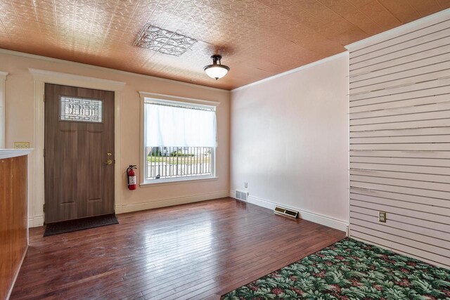 foyer entrance featuring visible vents, ornamental molding, an ornate ceiling, and hardwood / wood-style flooring