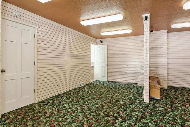 empty room featuring wooden walls and carpet flooring