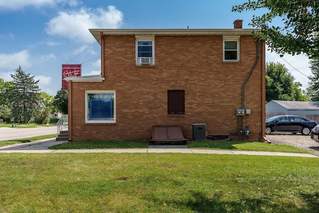 back of property featuring a lawn, central AC unit, brick siding, and a chimney