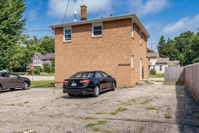 rear view of property with fence, a chimney, and brick siding