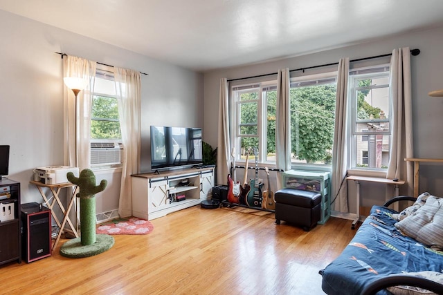 living area featuring a healthy amount of sunlight, cooling unit, and wood finished floors