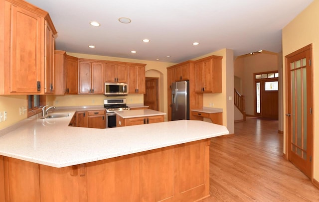 765 Safer Ct, Brookfield, WI 53045 - kitchen with a sink, a peninsula, stainless steel appliances, light wood-style flooring, and arched walkways