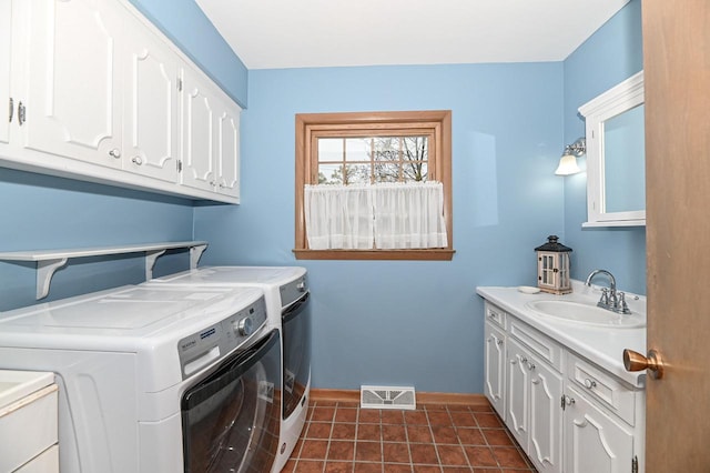 washroom with visible vents, dark tile patterned floors, washing machine and clothes dryer, a sink, and cabinet space