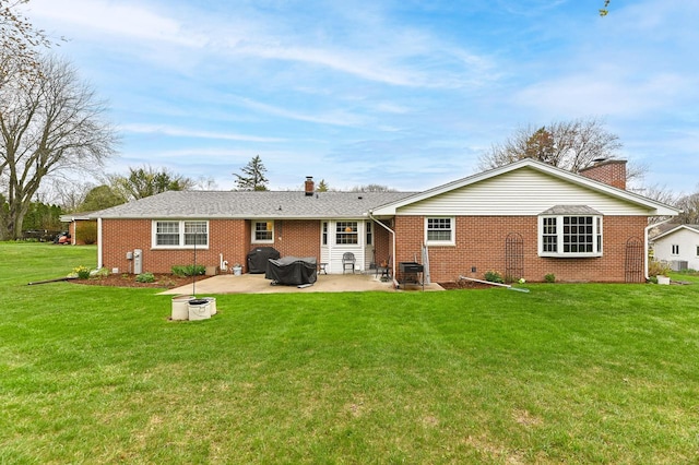 rear view of property with a lawn, a chimney, a patio area, and brick siding