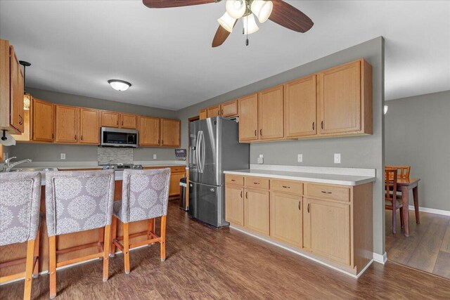 kitchen featuring ceiling fan, light countertops, a sink, dark wood finished floors, and stainless steel appliances