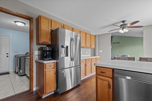 kitchen with light countertops, appliances with stainless steel finishes, ceiling fan, and washing machine and clothes dryer
