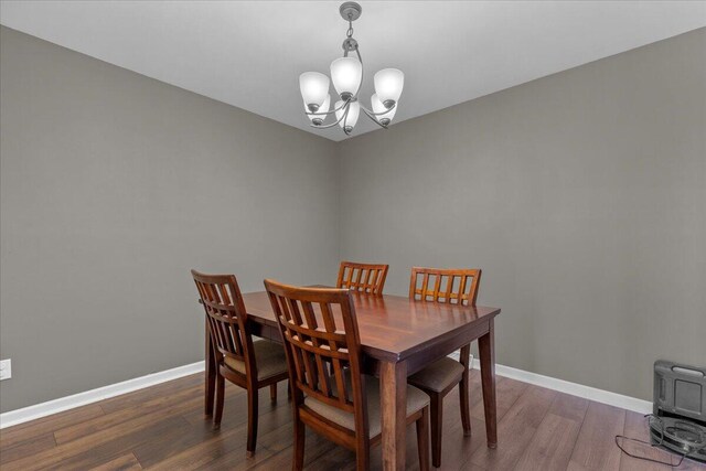 dining area with baseboards, wood finished floors, and a chandelier