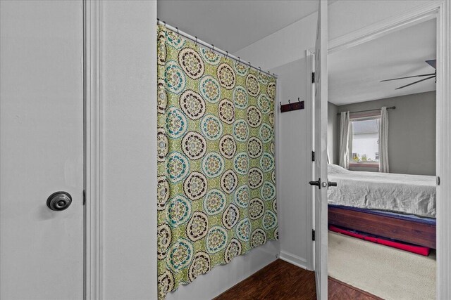 full bath with curtained shower and wood finished floors