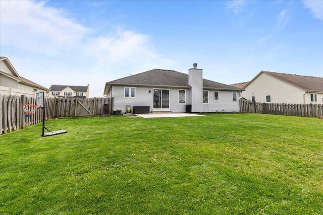 rear view of property with a fenced backyard, a chimney, a yard, and a patio area