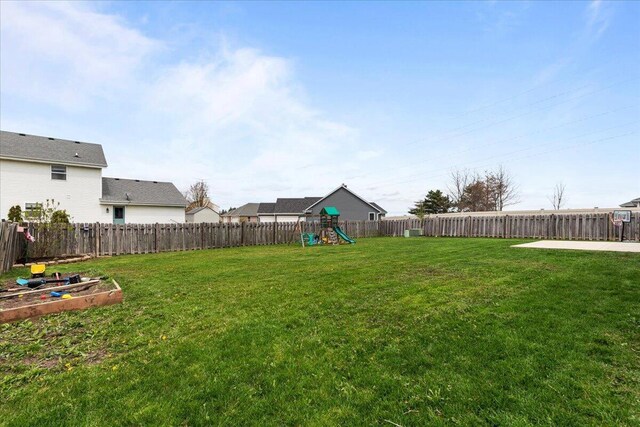 view of yard featuring a playground, a fenced backyard, and a vegetable garden