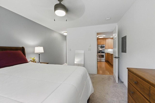 bedroom featuring a ceiling fan, light carpet, and electric panel