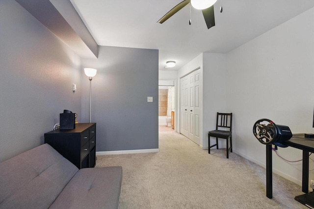 sitting room with baseboards, ceiling fan, and light carpet