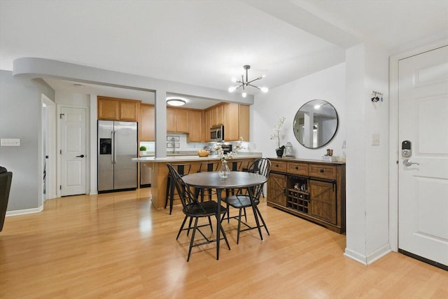 dining room featuring light wood-style floors, baseboards, and an inviting chandelier