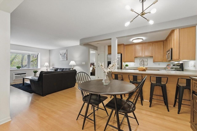dining area with light wood-style floors, a wall unit AC, and a chandelier