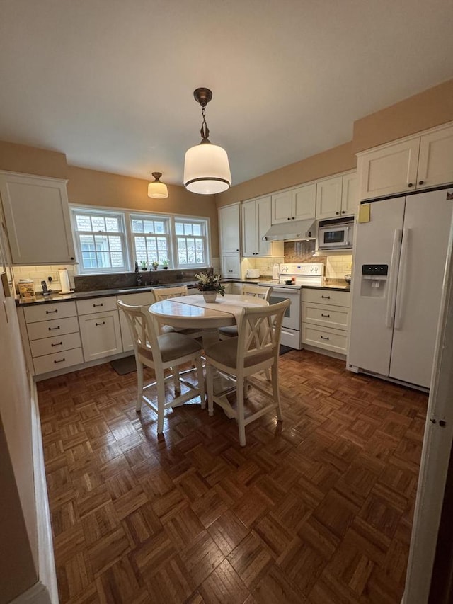 3216 Moorland Ave, Racine, WI 53405 - kitchen featuring white appliances, white cabinets, under cabinet range hood, and decorative backsplash