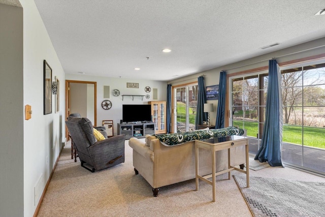 living area with light colored carpet, recessed lighting, a textured ceiling, and visible vents