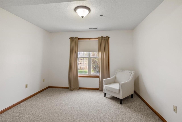 sitting room featuring visible vents, a textured ceiling, baseboards, and light colored carpet