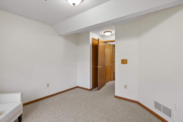 interior space with light colored carpet, baseboards, visible vents, and vaulted ceiling