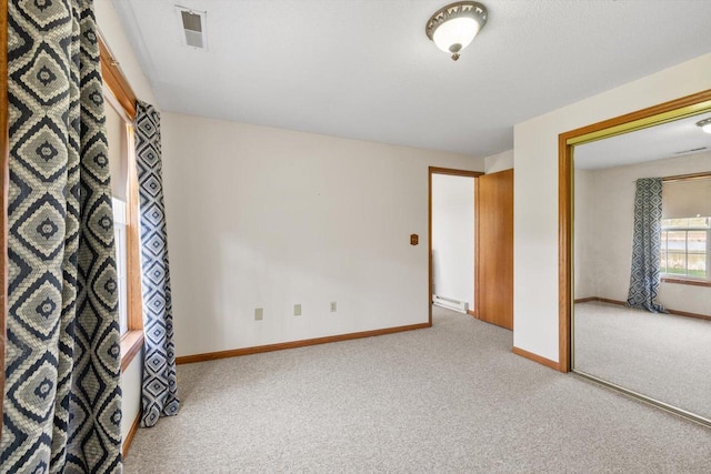 carpeted spare room featuring visible vents, baseboards, and a baseboard heating unit