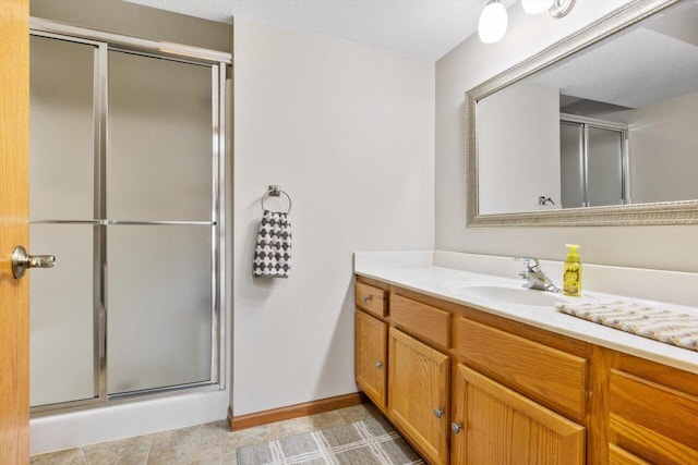 full bath featuring vanity, baseboards, and a stall shower