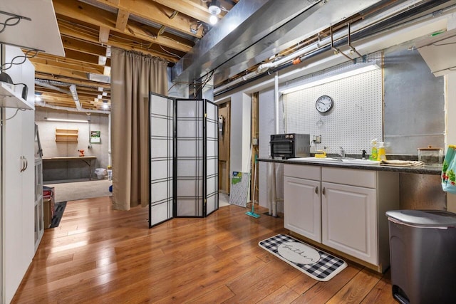 unfinished basement with a sink and wood-type flooring