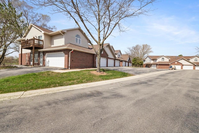 view of front of home with brick siding, a residential view, a balcony, and aphalt driveway