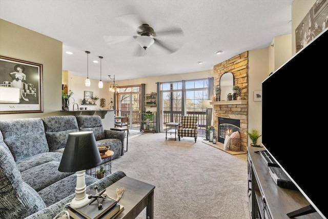 carpeted living room with a textured ceiling, ceiling fan, and a stone fireplace