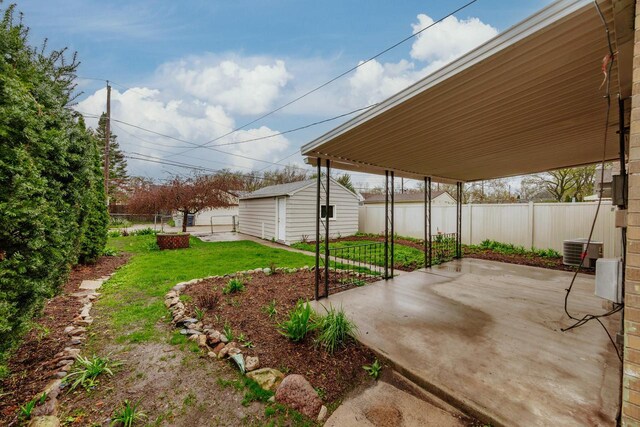 view of yard with central air condition unit, an outdoor structure, a fenced backyard, and a patio area