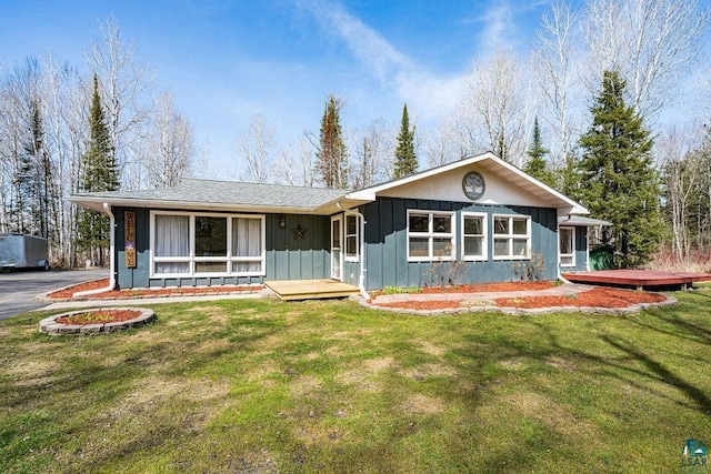 ranch-style home featuring a wooden deck, board and batten siding, and a front lawn