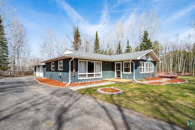 ranch-style house featuring a garage, board and batten siding, aphalt driveway, and a front yard