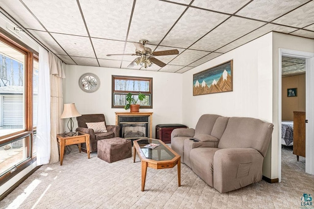 living room with light colored carpet, a glass covered fireplace, ceiling fan, and a drop ceiling