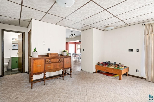 interior space featuring baseboards, a paneled ceiling, and light colored carpet