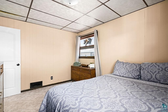 bedroom with carpet floors, wooden walls, visible vents, and a drop ceiling