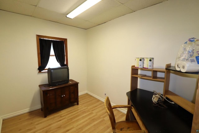 office area featuring baseboards, a drop ceiling, and light wood finished floors
