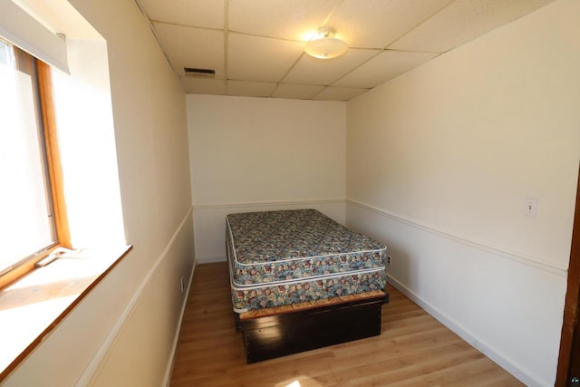 bedroom featuring a drop ceiling and light wood-type flooring