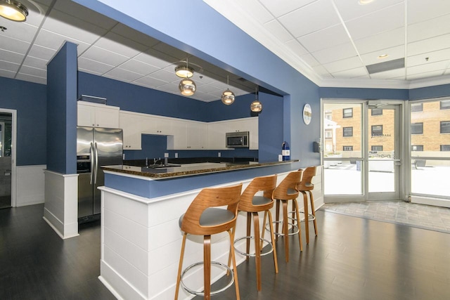 kitchen featuring dark countertops, appliances with stainless steel finishes, a sink, a drop ceiling, and wood finished floors