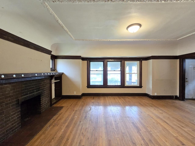 unfurnished living room with baseboards, hardwood / wood-style floors, and a fireplace