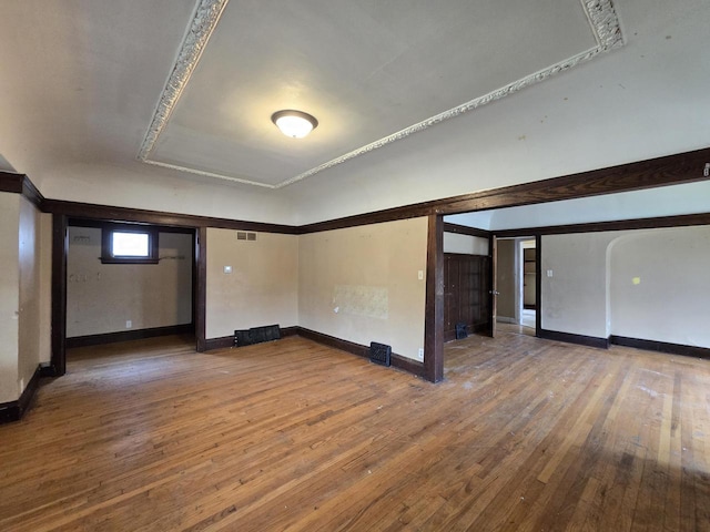 empty room featuring wood-type flooring, baseboards, and visible vents
