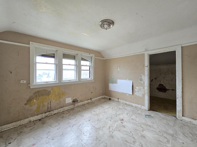 additional living space featuring baseboards and vaulted ceiling