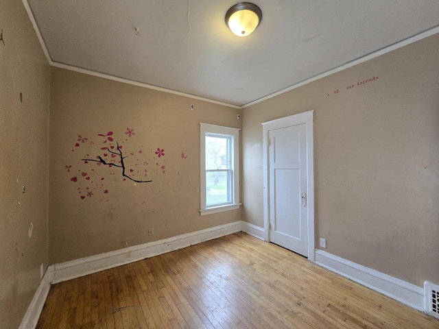 spare room with baseboards, visible vents, ornamental molding, and light wood-style flooring