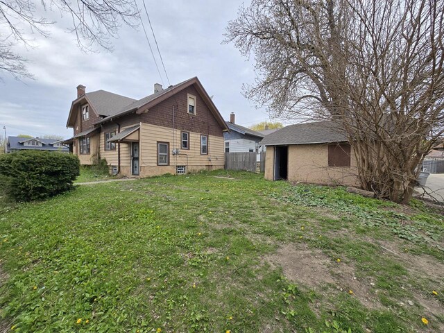 view of side of property featuring a lawn, fence, and a chimney
